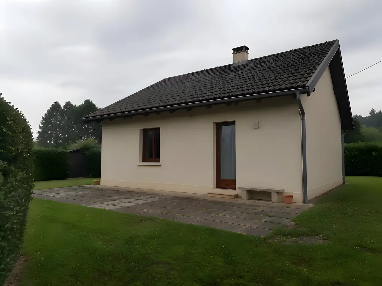 Maison de plain-pied à l'enduit crème vue du jardin, vieille terrasse en dalles, avant l'agrandissement