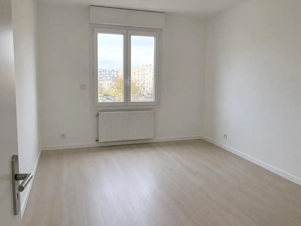 La même pièce aux murs et au plafond d'un blanc mat égal, radiateur blanc sous la fenêtre