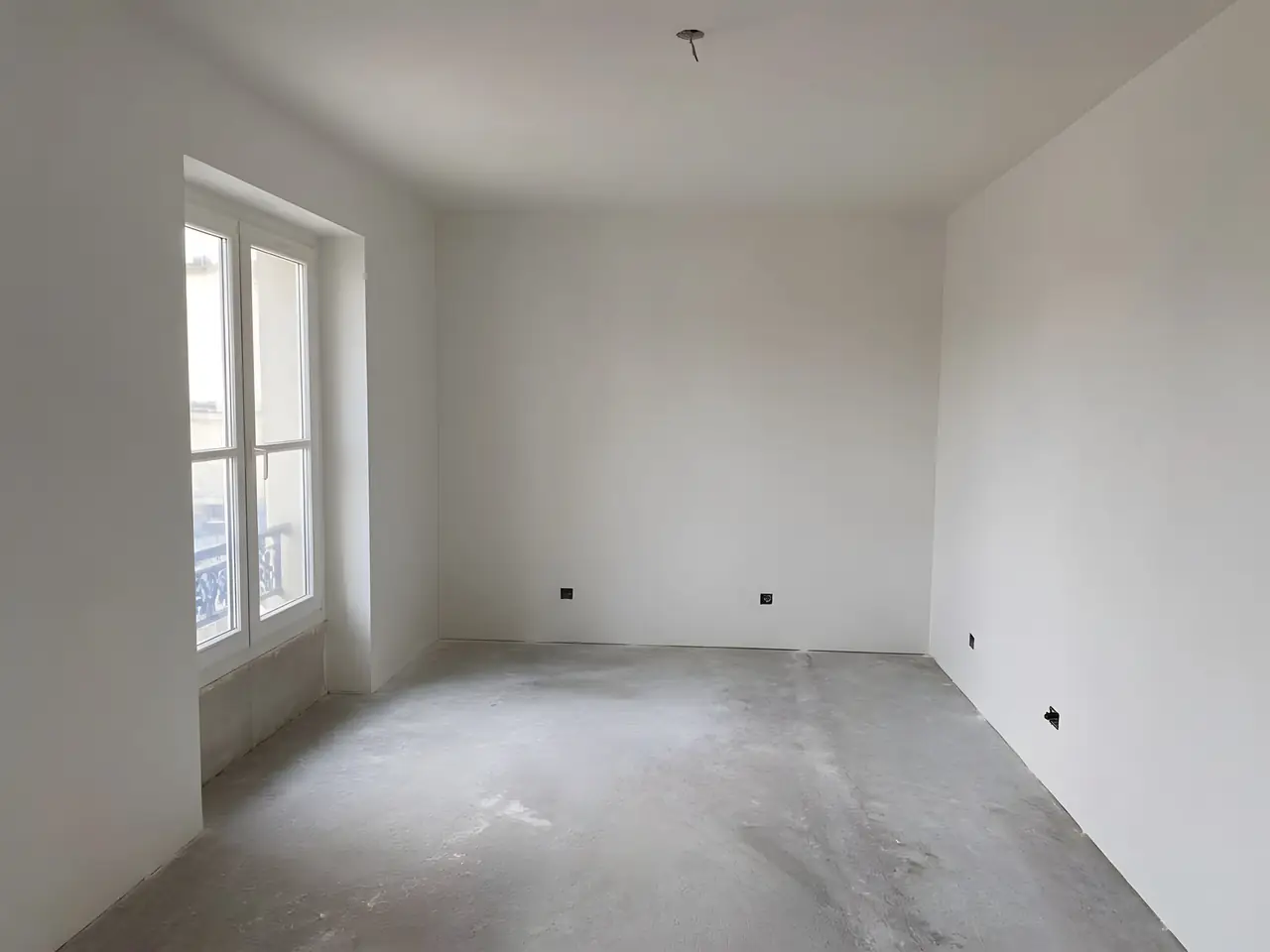 La même pièce aux murs et au plafond d'un blanc uni, plus aucune bande visible, sol encore brut
