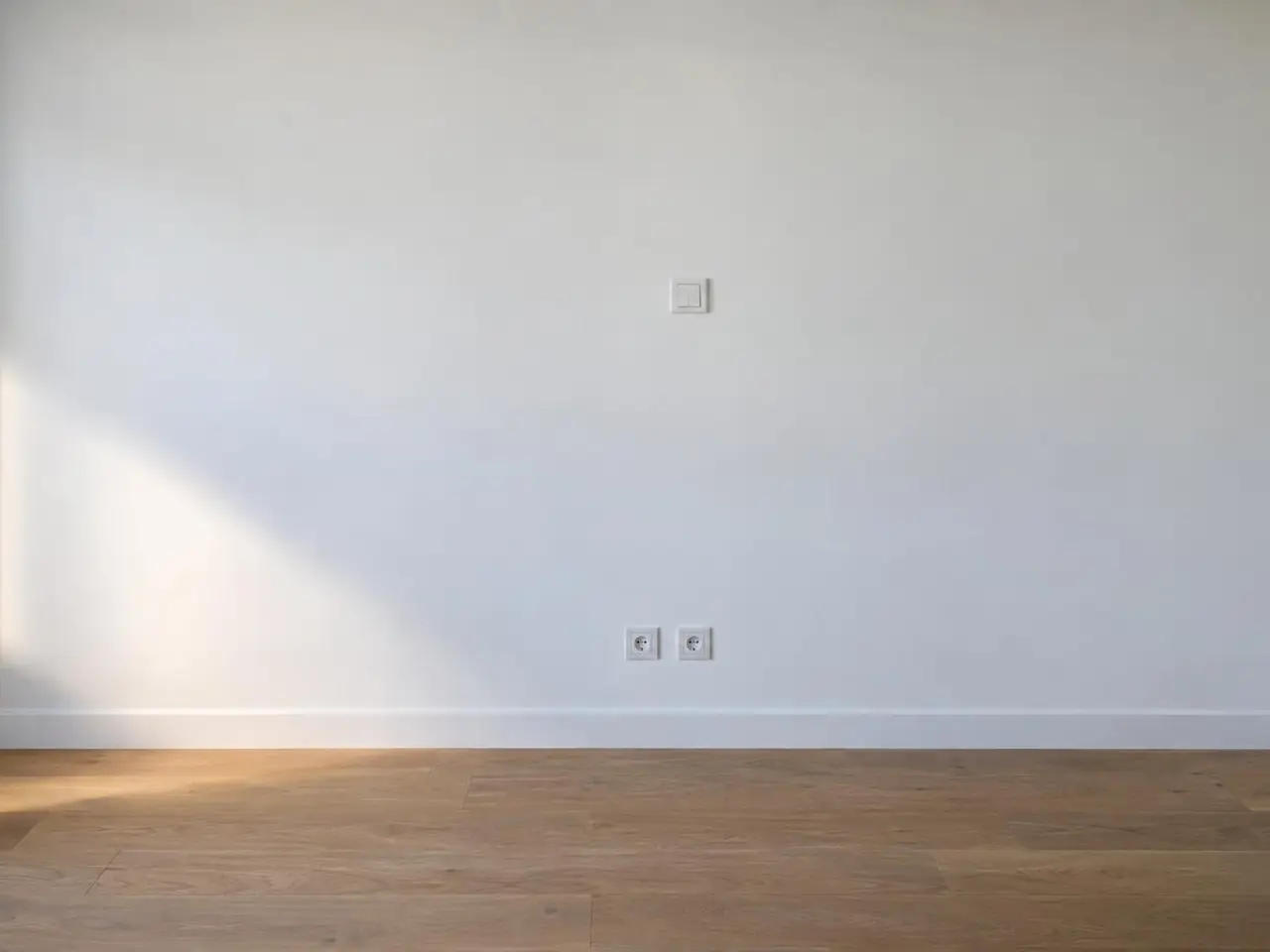 Le même mur lisse et blanc, interrupteur et prises posés à leur place, sans aucune trace de saignée