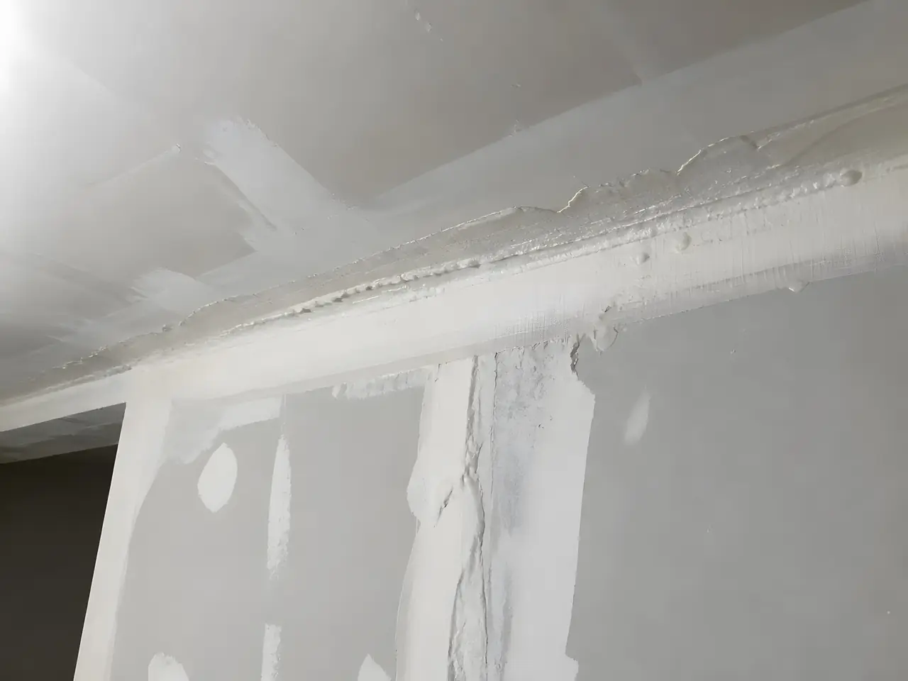 Angle de mur et de plafond en plaques, joints couverts d'une bande épaisse et d'enduit en paquets