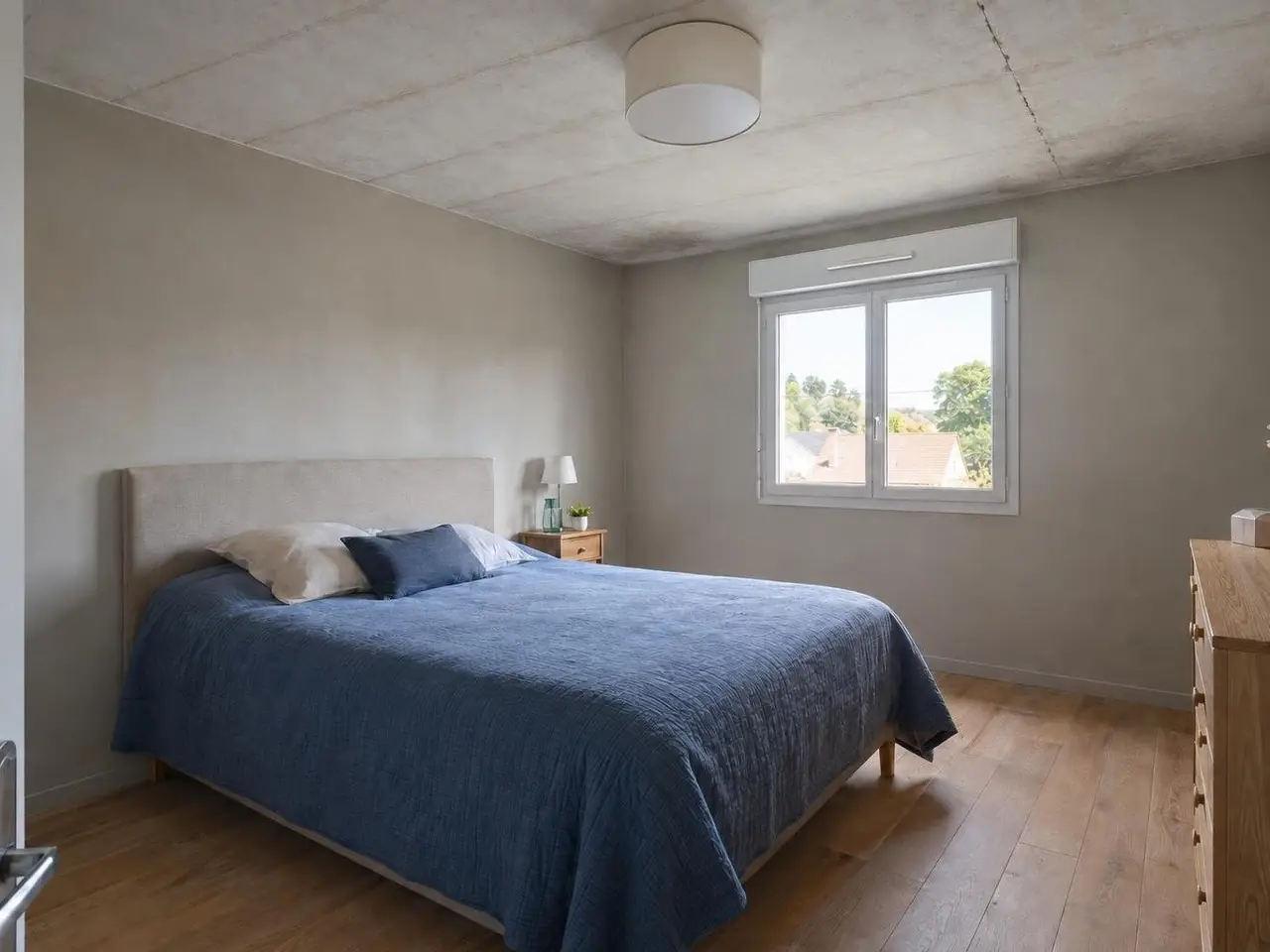 Chambre sous le grenier au plafond gris terne, marqué de lignes de joints régulières et d'une longue fissure