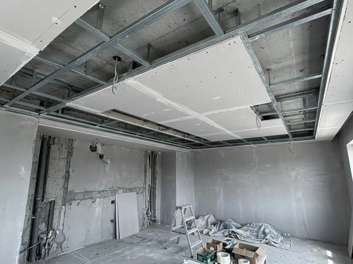 Rails métal suspendus sous la vieille dalle, premières plaques vissées dessus, fils des luminaires ressortis