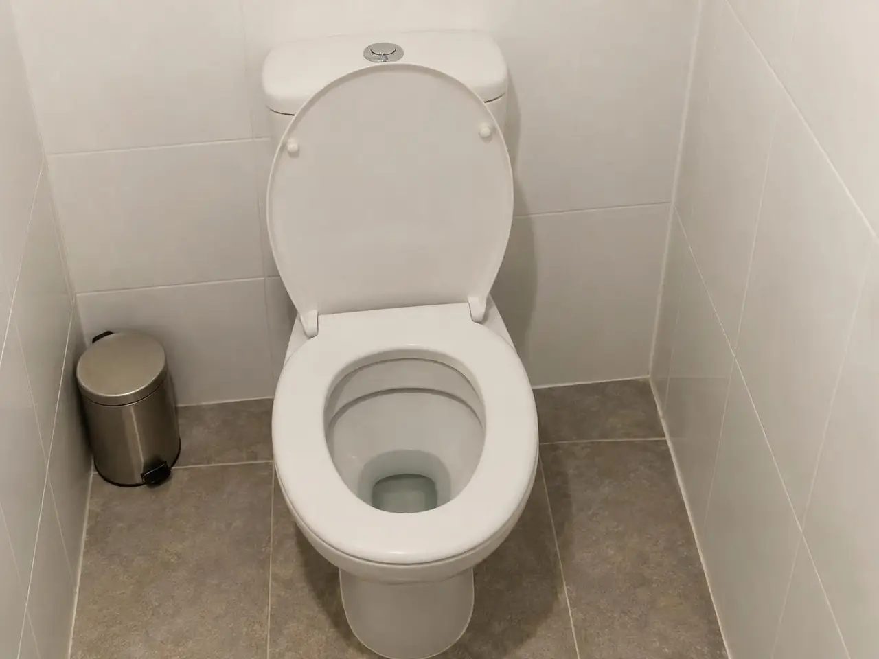 Cuvette de WC blanche abattant relevé, émail propre, eau claire et immobile au fond, réservoir blanc derrière